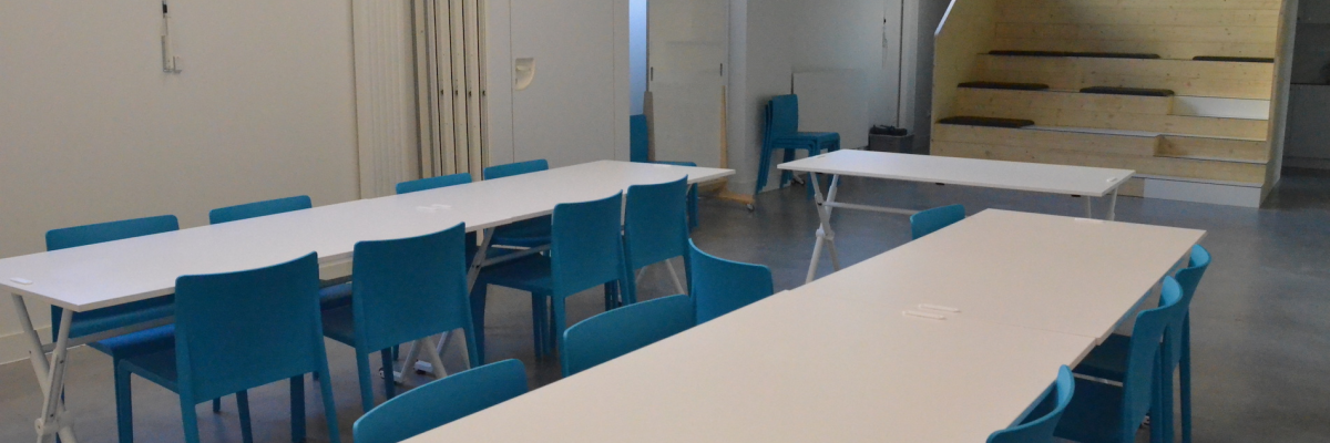 Salle avec tables, chaises, étagères et escaliers.