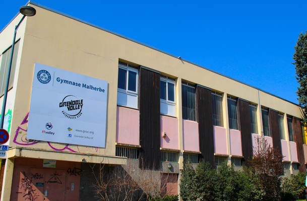 Gymnase avec panneaux d'affichage, fenêtres et végétation.