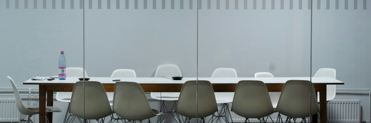 Table de réunion avec chaises, bouteille d'eau et radiateur visible à travers une vitre.