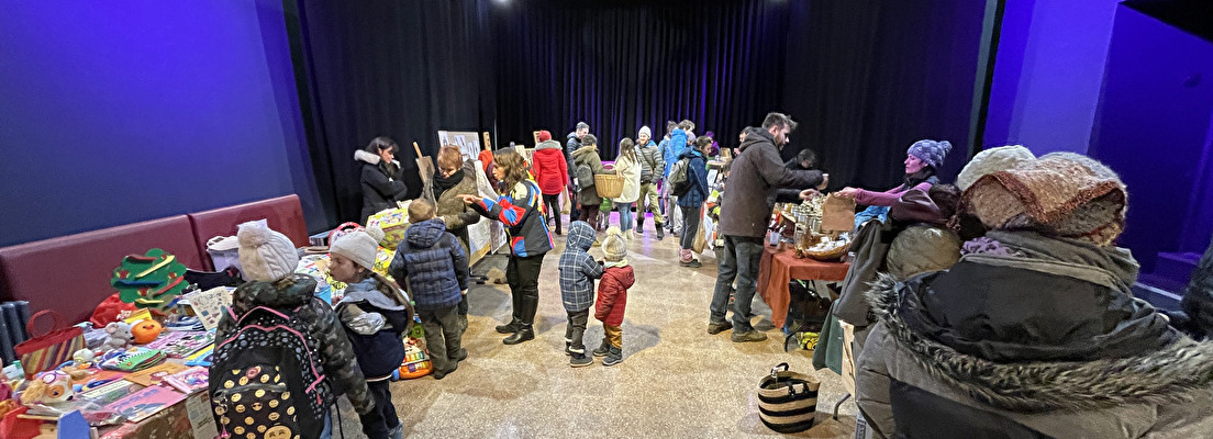 Salle avec tables, nourriture, personnes et rideaux bleus.