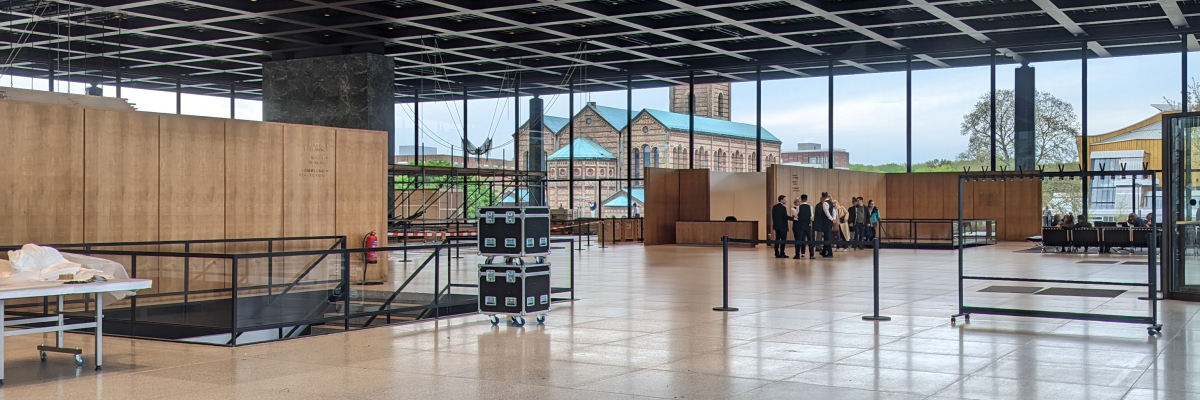 Grand espace avec plafond à panneaux, grandes fenêtres, escaliers, et tables.
