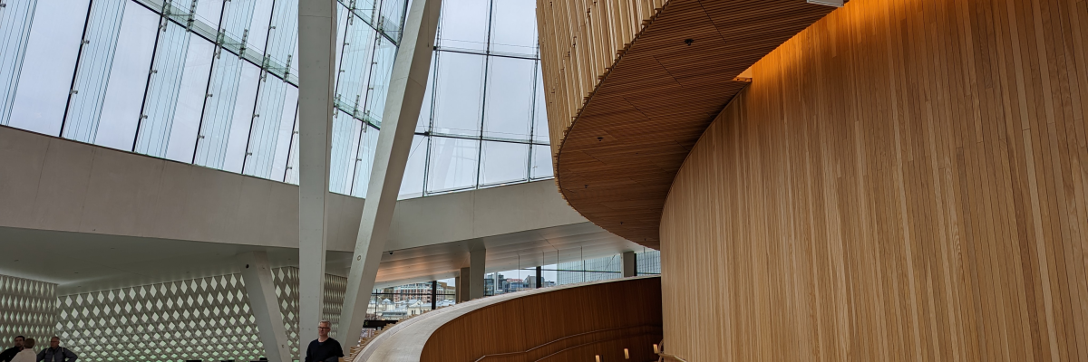 Espace moderne avec rampes en bois, murs en verre, et quelques personnes.