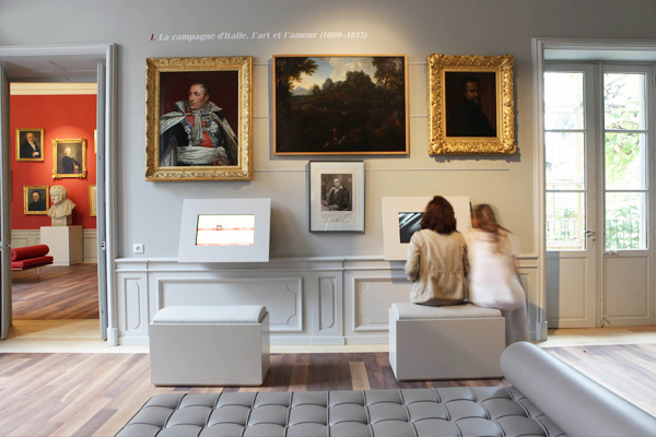 Salle avec tableaux, canapé, écran, porte et fenêtre.