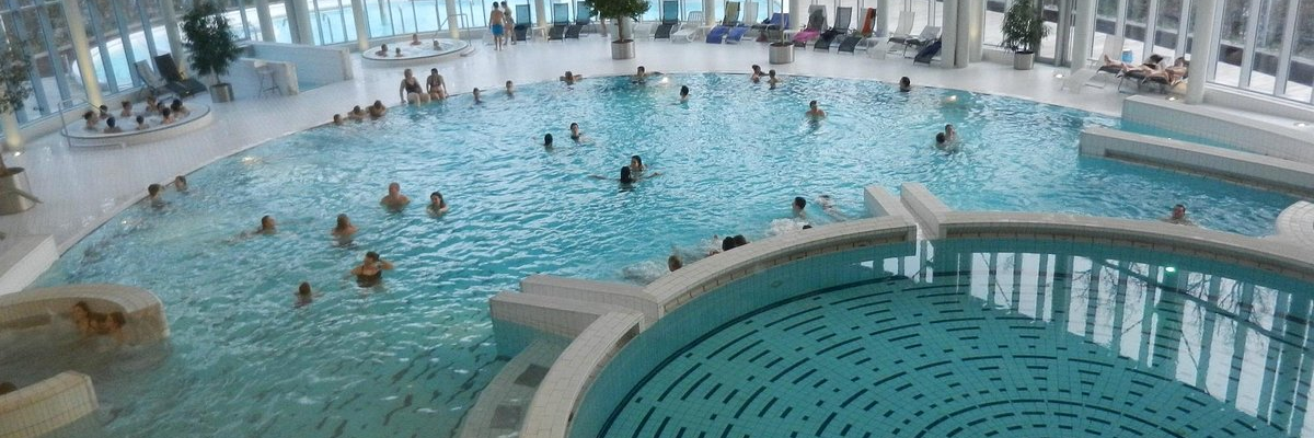 Grand bassin et petits bassins intérieurs avec personnes nageant et relaxant.