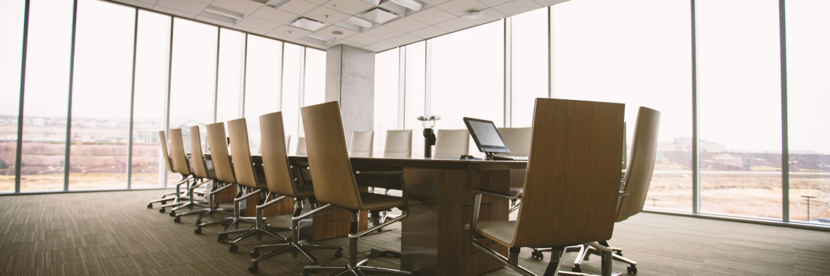 "Salle de réunion avec table, chaises, ordinateur portable et projecteur suspendu."