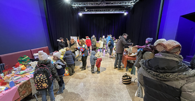 Salle avec tables, nourriture, personnes et rideaux bleus.